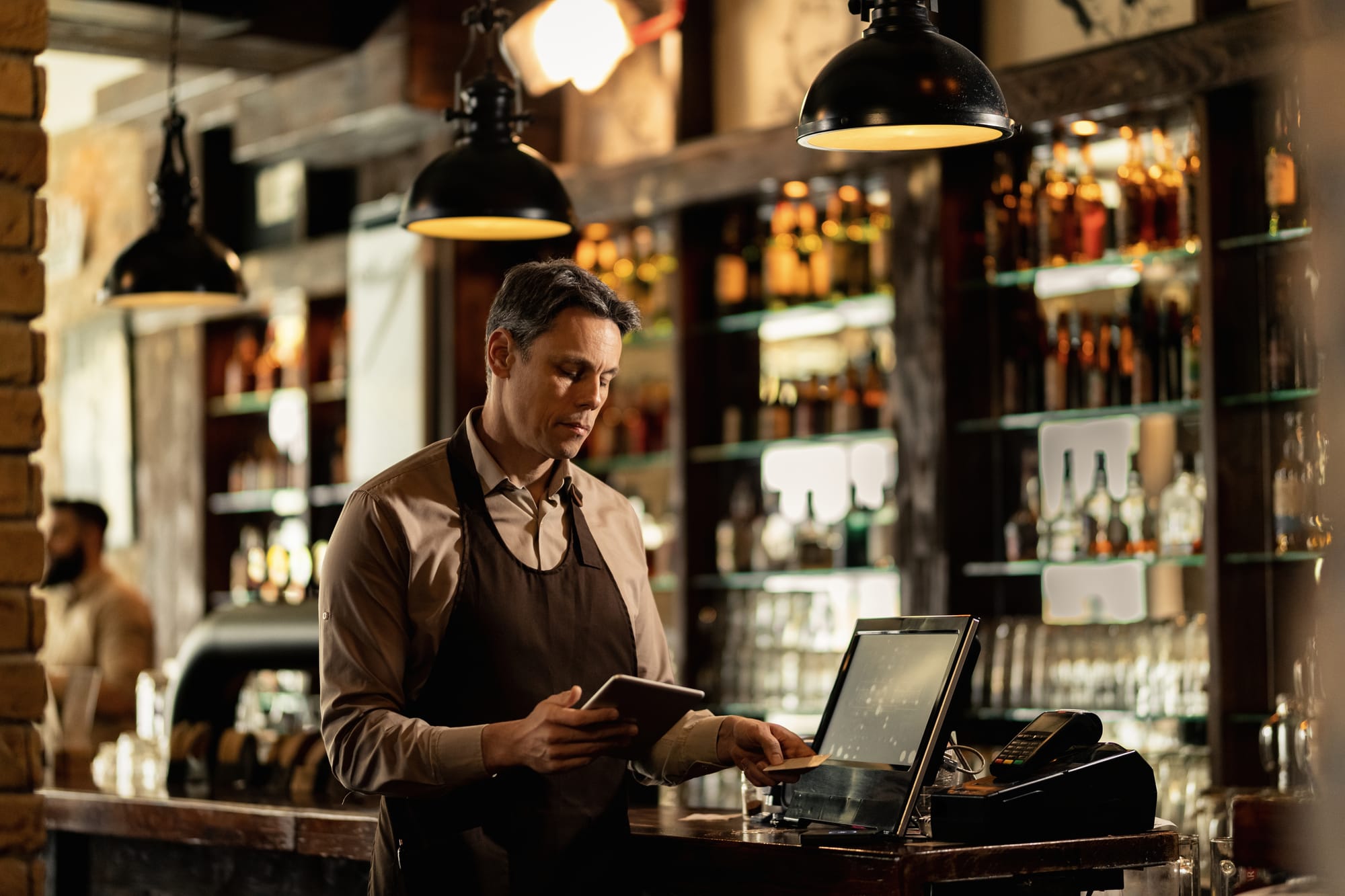 Barman werkt met het kassascherm achter de bar