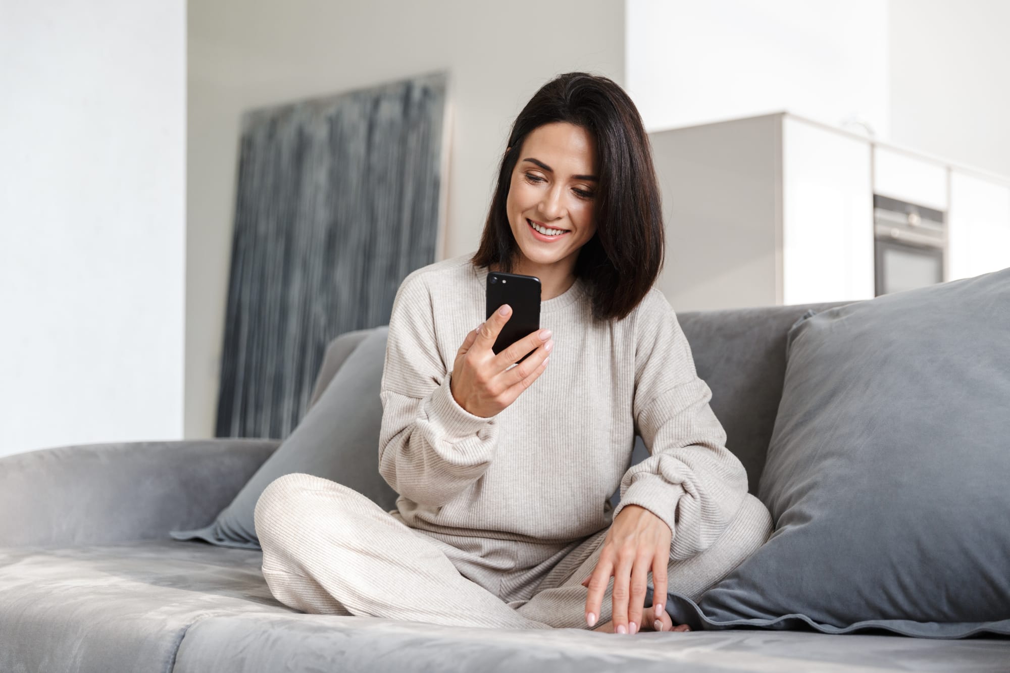 Vrouw scrolt op haar telefoon op de bank