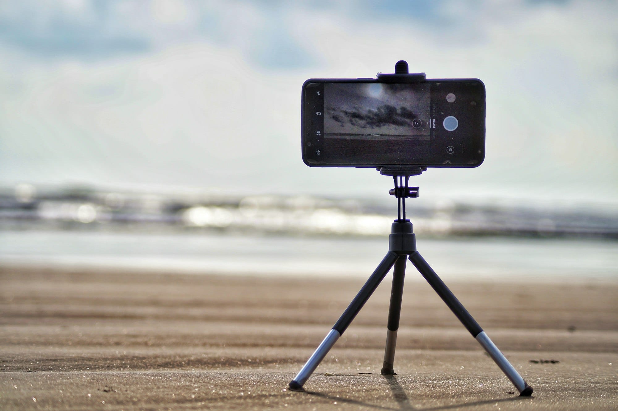 Smartphone op een klein statief op het strand