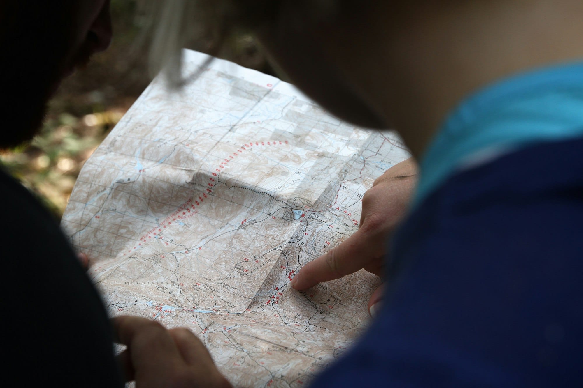 Iemand wijst een route aan op een opengevouwen papieren kaart