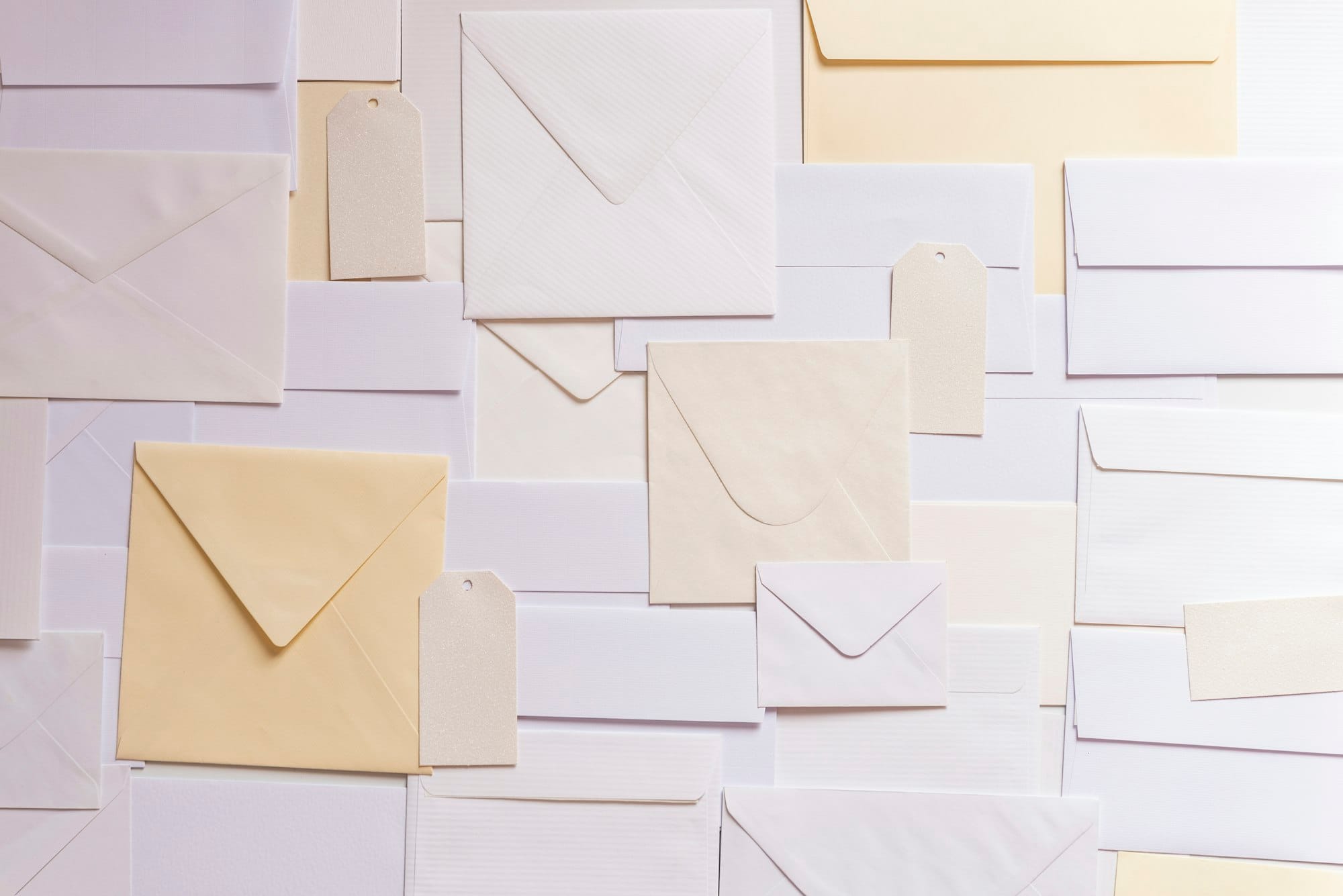 Enveloppen, papiersoorten en labels in zachte crèmetinten naast elkaar
