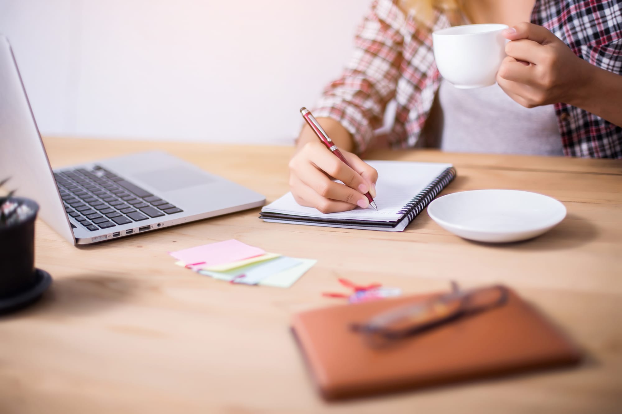 Hand schrijft notities naast een laptop en geeltjes