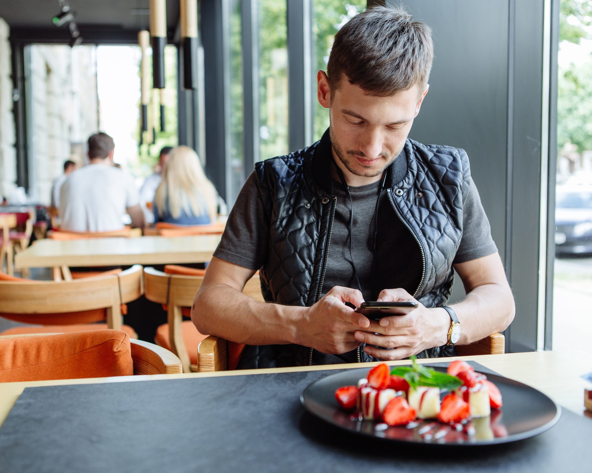 Man fotografeert zijn gerecht met zijn telefoon in een restaurant