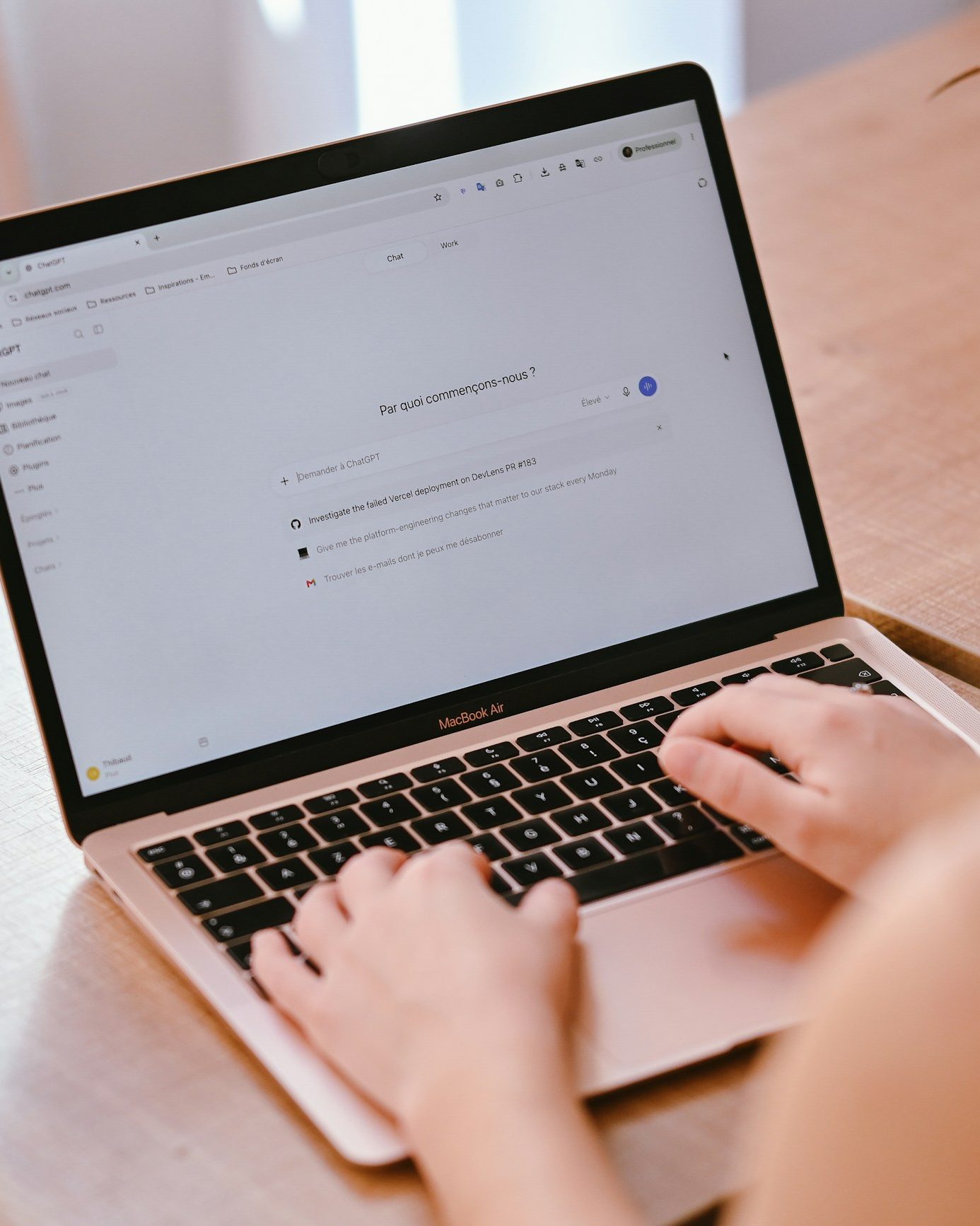 Iemand typt een zoekvraag op een laptop aan een houten tafel